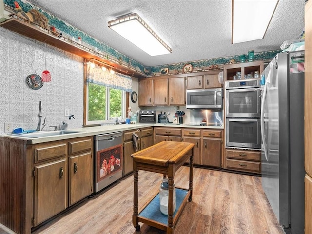 1490 216th St, Lathrop, MO 64465 - kitchen featuring stainless steel appliances, light wood-style floors, light countertops, a textured ceiling, and brown cabinetry
