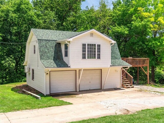 1490 216th St, Lathrop, MO 64465 - view of front of house with a shingled roof, concrete driveway, a garage, stairs, and a front yard