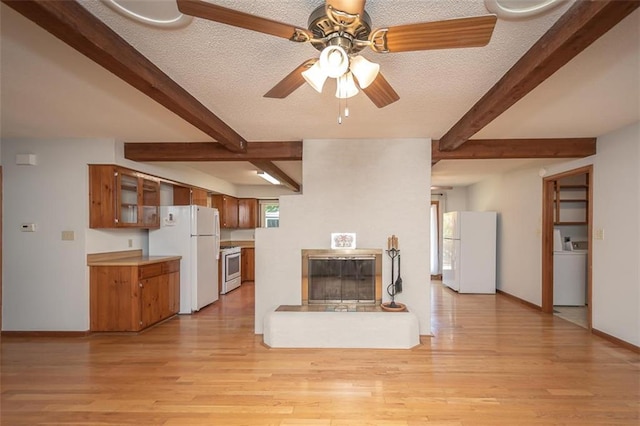918 King St, Baldwin City, KS 66006 - unfurnished living room featuring washer / clothes dryer, beam ceiling, a large fireplace, light wood finished floors, and a ceiling fan