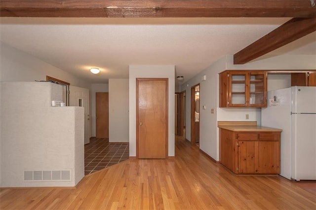 918 King St, Baldwin City, KS 66006 - kitchen with freestanding refrigerator, light wood-style flooring, brown cabinetry, and glass insert cabinets