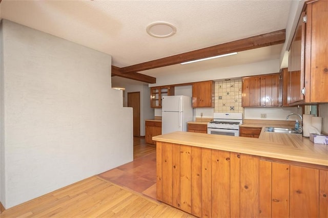 918 King St, Baldwin City, KS 66006 - kitchen with white appliances, beamed ceiling, a peninsula, light countertops, and brown cabinets