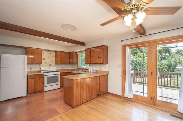 918 King St, Baldwin City, KS 66006 - kitchen featuring white appliances, beam ceiling, a peninsula, light countertops, and brown cabinetry