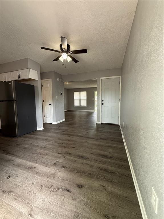 401-07 NE Highland Ln, Blue Springs, MO 64014 - unfurnished living room with a textured wall, a textured ceiling, dark wood finished floors, and a ceiling fan