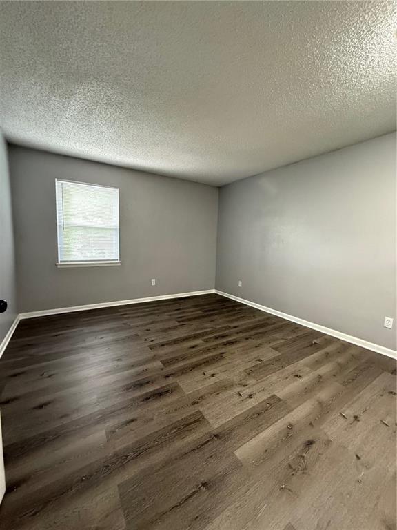 401-07 NE Highland Ln, Blue Springs, MO 64014 - spare room with a textured ceiling and dark wood-style flooring