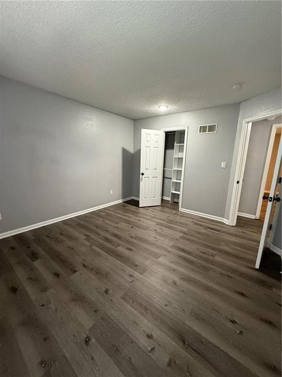 401-07 NE Highland Ln, Blue Springs, MO 64014 - unfurnished bedroom with a textured ceiling, dark wood finished floors, and a closet