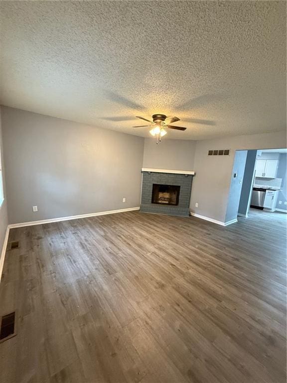 401-07 NE Highland Ln, Blue Springs, MO 64014 - unfurnished living room with a ceiling fan, dark wood-type flooring, a textured ceiling, and a fireplace