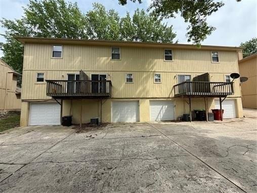 401-07 NE Highland Ln, Blue Springs, MO 64014 - rear view of house with an attached garage, driveway, and a deck
