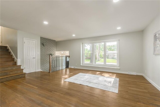 9909 Juniper Ln, Overland Park, KS 66207 - unfurnished living room with wood finished floors, recessed lighting, and stairway