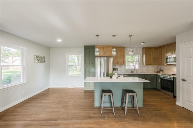 9909 Juniper Ln, Overland Park, KS 66207 - kitchen featuring appliances with stainless steel finishes, a kitchen bar, tasteful backsplash, light countertops, and healthy amount of natural light