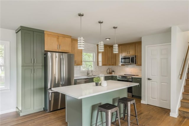 9909 Juniper Ln, Overland Park, KS 66207 - kitchen with stainless steel appliances, wood finished floors, decorative backsplash, light countertops, and a center island