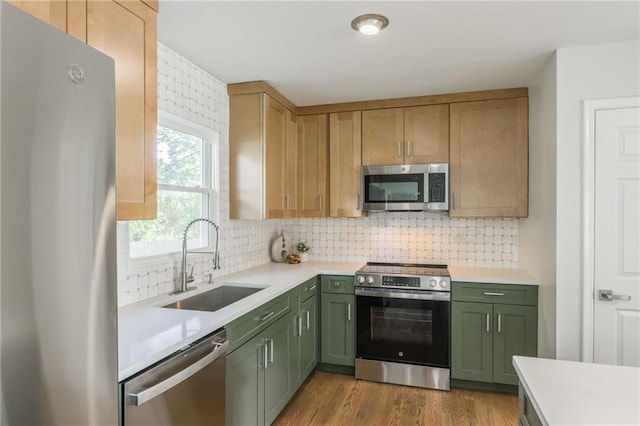 9909 Juniper Ln, Overland Park, KS 66207 - kitchen with stainless steel appliances, green cabinetry, light countertops, and decorative backsplash