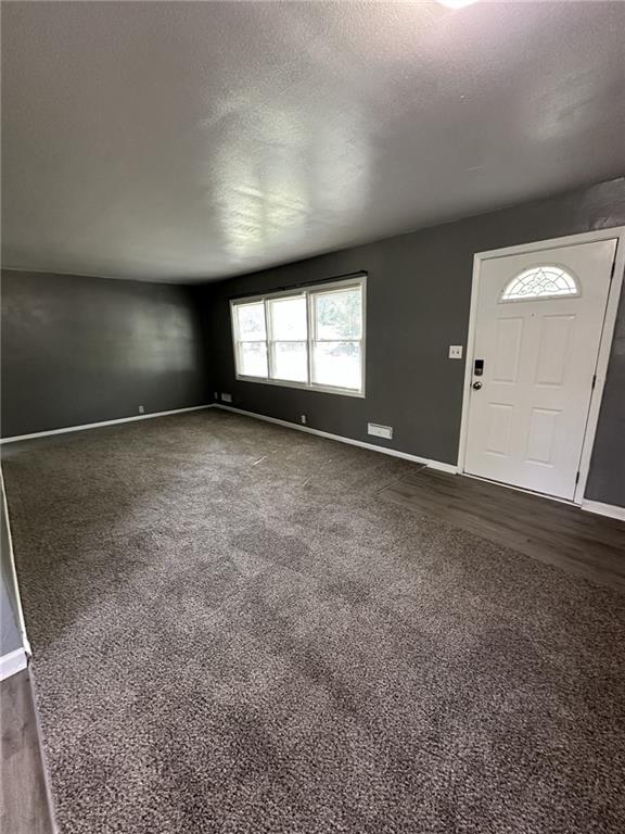 11001 Ewing Ave, Kansas City, MO 64134 - entryway featuring dark carpet and a textured ceiling
