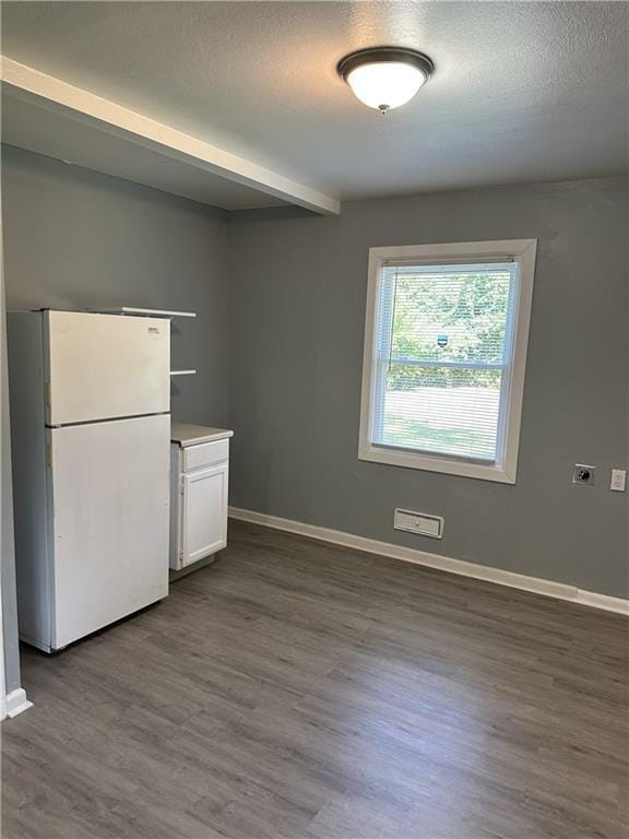 11001 Ewing Ave, Kansas City, MO 64134 - kitchen with freestanding refrigerator, dark wood-style floors, white cabinets, beam ceiling, and a textured ceiling