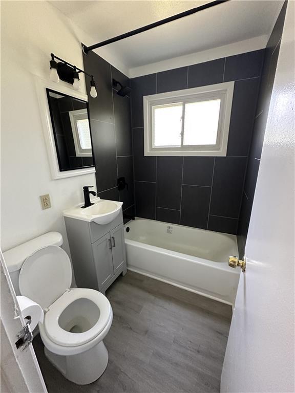 11001 Ewing Ave, Kansas City, MO 64134 - full bathroom with bathing tub / shower combination, vanity, and wood finished floors