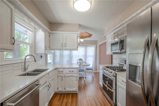 1921 SW 4th St, Lees Summit, MO 64081 - kitchen with stainless steel appliances, a textured ceiling, light countertops, white cabinetry, and decorative backsplash