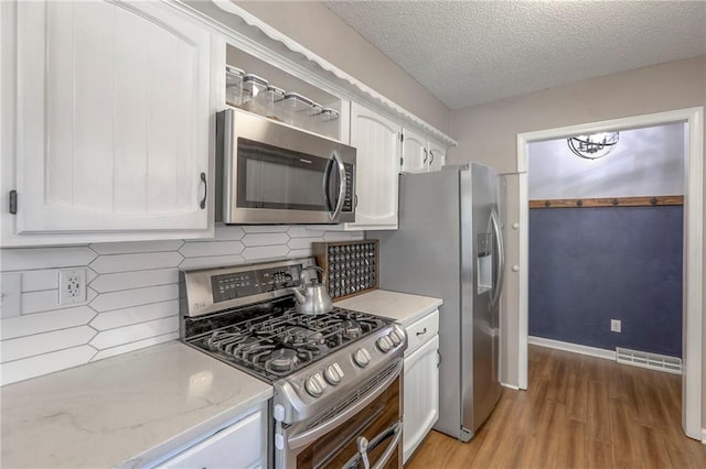 1921 SW 4th St, Lees Summit, MO 64081 - kitchen featuring stainless steel appliances, light wood finished floors, white cabinetry, backsplash, and a textured ceiling