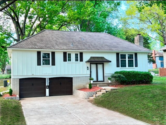 10806 W 96th St, Overland Park, KS 66214 - raised ranch featuring a chimney, an attached garage, driveway, board and batten siding, and brick siding