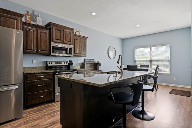 21904 Crystal Ave, Peculiar, MO 64078 - kitchen featuring appliances with stainless steel finishes, a breakfast bar, a kitchen island with sink, dark wood finished floors, and recessed lighting