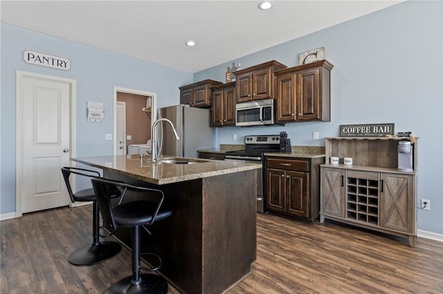 21904 Crystal Ave, Peculiar, MO 64078 - kitchen featuring stainless steel appliances, dark wood-style flooring, an island with sink, a breakfast bar area, and recessed lighting