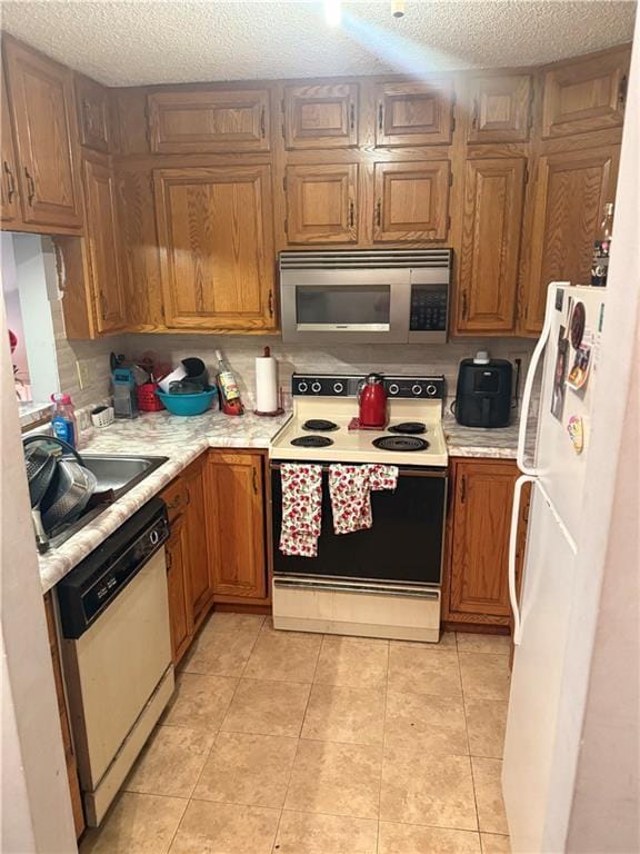 8135 Holmes Rd Unit 202, Kansas City, MO 64131 - kitchen with white appliances, light countertops, a textured ceiling, brown cabinets, and light tile patterned floors
