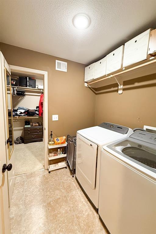 12748 Walker Ave, Kansas City, KS 66109 - laundry area with washing machine and clothes dryer and a textured ceiling