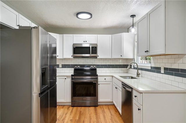 1304 E 41st St, Kansas City, MO 64110 - kitchen with stainless steel appliances, a textured ceiling, light wood-style floors, and white cabinetry