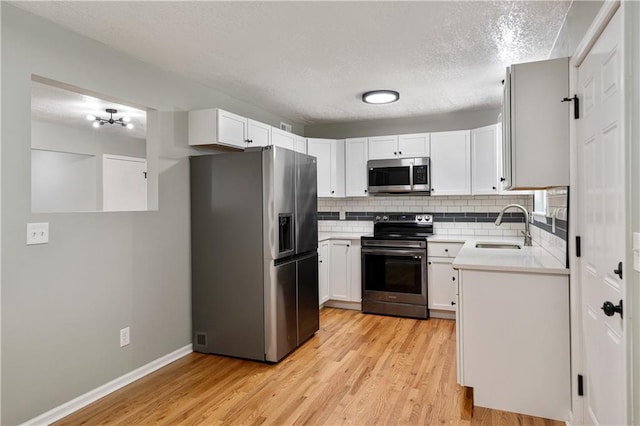 1304 E 41st St, Kansas City, MO 64110 - kitchen with appliances with stainless steel finishes, backsplash, a textured ceiling, light countertops, and light wood-style floors