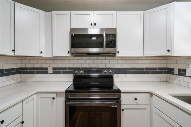 1304 E 41st St, Kansas City, MO 64110 - kitchen with appliances with stainless steel finishes, white cabinetry, backsplash, and light countertops