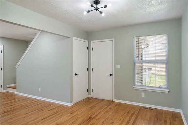 1304 E 41st St, Kansas City, MO 64110 - entrance foyer with light wood-style flooring, a textured ceiling, stairway, and a chandelier