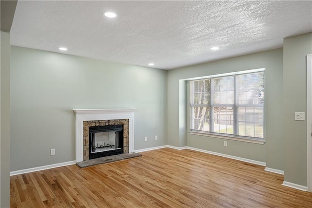 1304 E 41st St, Kansas City, MO 64110 - unfurnished living room with wood finished floors, a textured ceiling, recessed lighting, and a fireplace
