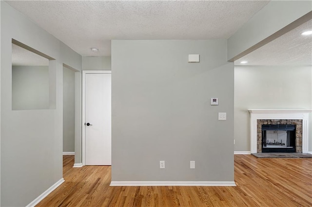 1304 E 41st St, Kansas City, MO 64110 - unfurnished living room with wood finished floors, a fireplace, a textured ceiling, and recessed lighting