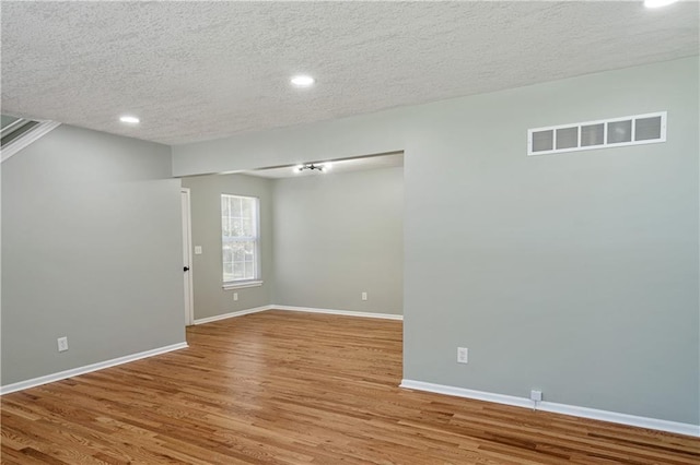 1304 E 41st St, Kansas City, MO 64110 - empty room with wood finished floors, a textured ceiling, and recessed lighting