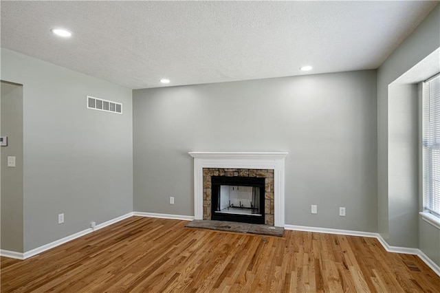 1304 E 41st St, Kansas City, MO 64110 - unfurnished living room with wood finished floors, a textured ceiling, recessed lighting, and a fireplace