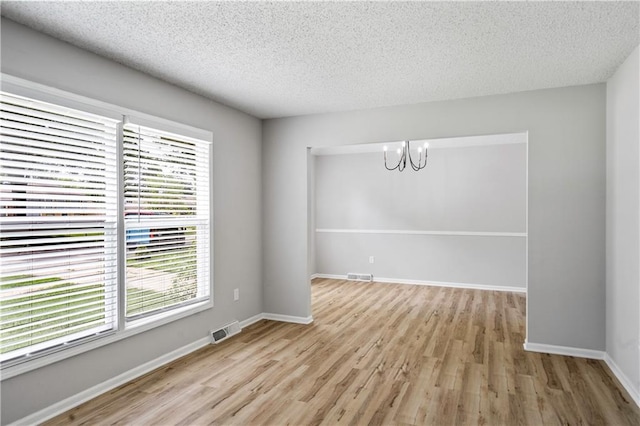 16620 E 36th St, Independence, MO 64055 - unfurnished room featuring plenty of natural light, a chandelier, wood finished floors, and a textured ceiling