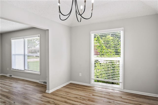 16620 E 36th St, Independence, MO 64055 - empty room featuring a chandelier, a textured ceiling, and wood finished floors
