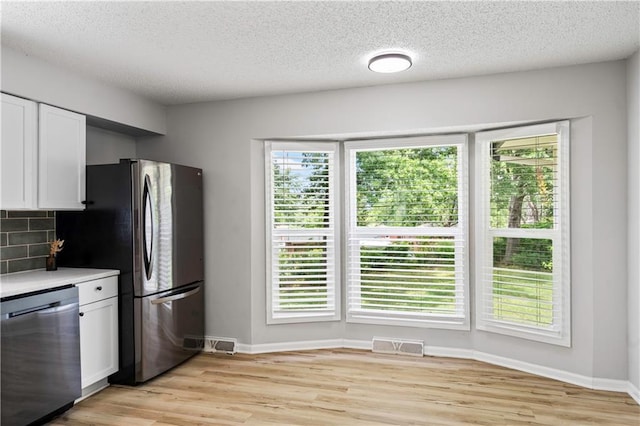 16620 E 36th St, Independence, MO 64055 - kitchen with appliances with stainless steel finishes, white cabinets, light wood-style flooring, backsplash, and light countertops