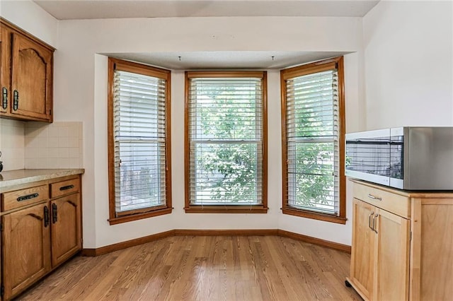 503 SE Brownfield Dr, Lees Summit, MO 64063 - kitchen featuring stainless steel microwave, light wood-type flooring, decorative backsplash, and healthy amount of natural light