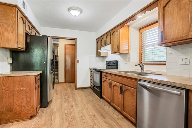 503 SE Brownfield Dr, Lees Summit, MO 64063 - kitchen featuring stainless steel appliances, under cabinet range hood, light wood finished floors, and brown cabinets