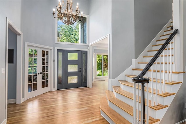 4140 W 131st Ter, Leawood, KS 66209 - foyer entrance with a towering ceiling, a chandelier, stairway, wood finished floors, and french doors