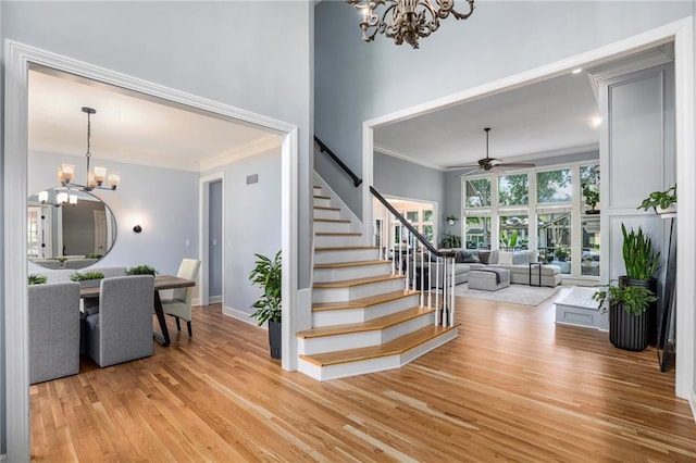 4140 W 131st Ter, Leawood, KS 66209 - stairs featuring a chandelier, a ceiling fan, wood finished floors, crown molding, and a towering ceiling