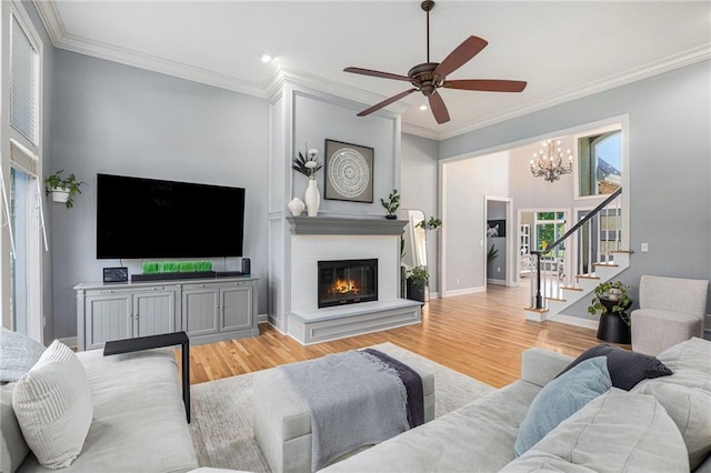 4140 W 131st Ter, Leawood, KS 66209 - living room featuring stairs, ornamental molding, light wood-style flooring, ceiling fan, and a chandelier