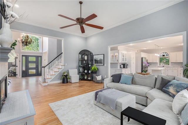 4140 W 131st Ter, Leawood, KS 66209 - living area with a chandelier, light wood finished floors, ceiling fan, stairway, and crown molding
