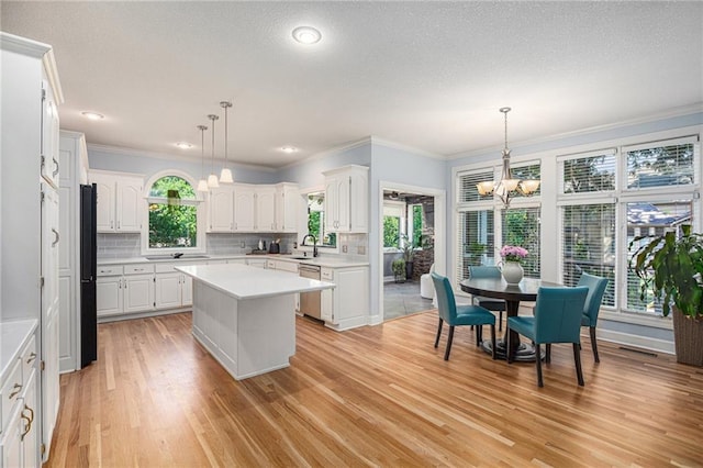 4140 W 131st Ter, Leawood, KS 66209 - kitchen with black appliances, a chandelier, light countertops, a center island, and white cabinetry