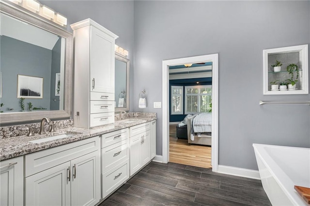 4140 W 131st Ter, Leawood, KS 66209 - ensuite bathroom featuring a freestanding tub, double vanity, wood finished floors, and a towering ceiling
