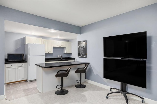 4140 W 131st Ter, Leawood, KS 66209 - kitchen with freestanding refrigerator, black microwave, a kitchen bar, white cabinetry, and dark countertops