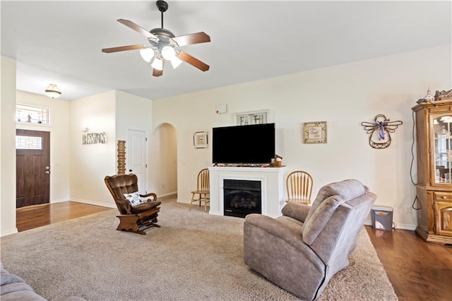 21506 Murlo Cir, Peculiar, MO 64078 - living area featuring arched walkways, ceiling fan, a fireplace, and wood finished floors