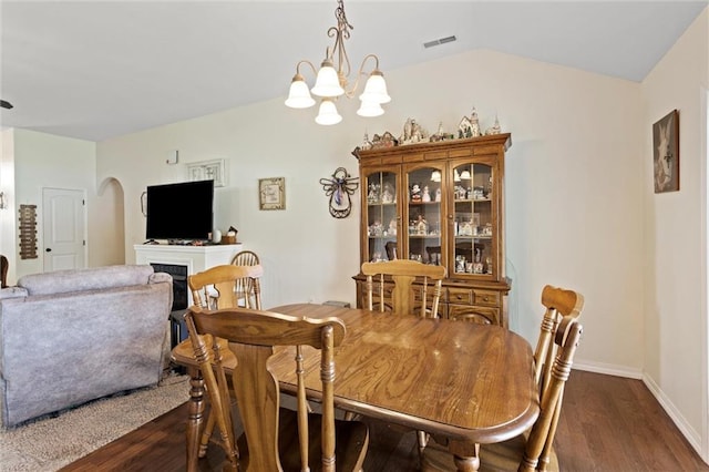 21506 Murlo Cir, Peculiar, MO 64078 - dining area featuring dark wood finished floors, arched walkways, a fireplace, a chandelier, and lofted ceiling