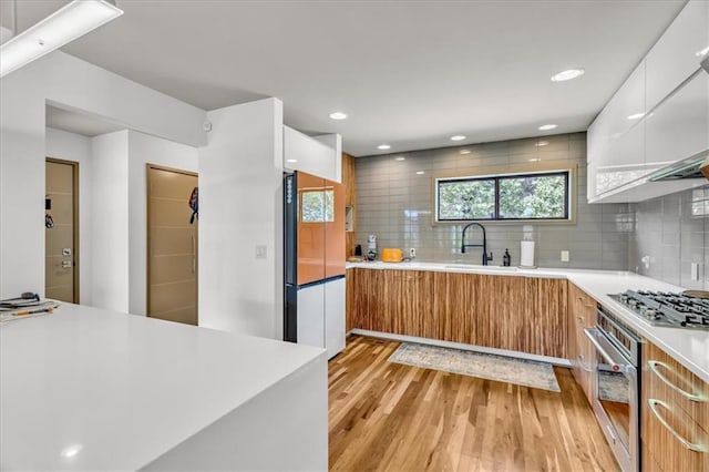 2400 Forest Ave, Kansas City, MO 64108 - kitchen with appliances with stainless steel finishes, modern cabinets, light wood-type flooring, light countertops, and recessed lighting