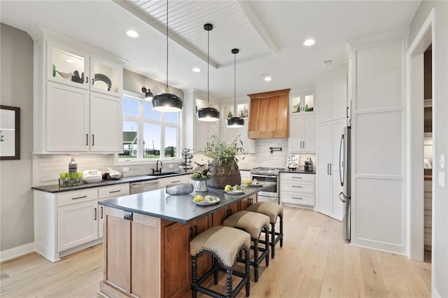 18608 Mohawk Ln, Overland Park, KS 66085 - kitchen featuring appliances with stainless steel finishes, light wood-style floors, dark countertops, a breakfast bar, and decorative backsplash