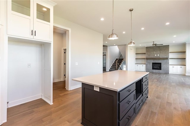 3361 W 187th St, Overland Park, KS 66085 - kitchen featuring white cabinetry, light wood-type flooring, light countertops, a center island, and a tiled fireplace